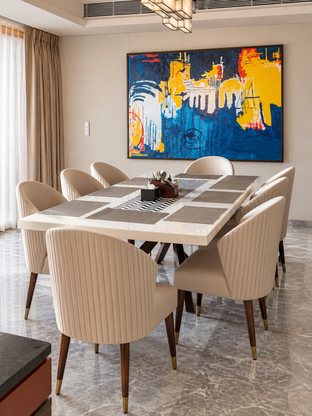 Dining room at The Ahmedabad Home – Client 103 with cream upholstered chairs and a large blue and yellow abstract artwork.