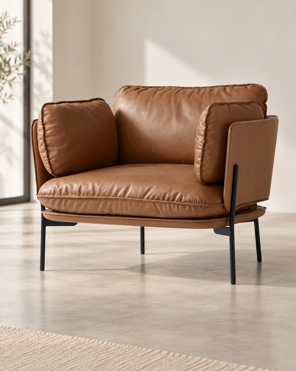 Generous tan cushions sit within a slim dark frame. The softly enclosed seat and lightly raised base give this armchair a relaxed, contemporary feel.