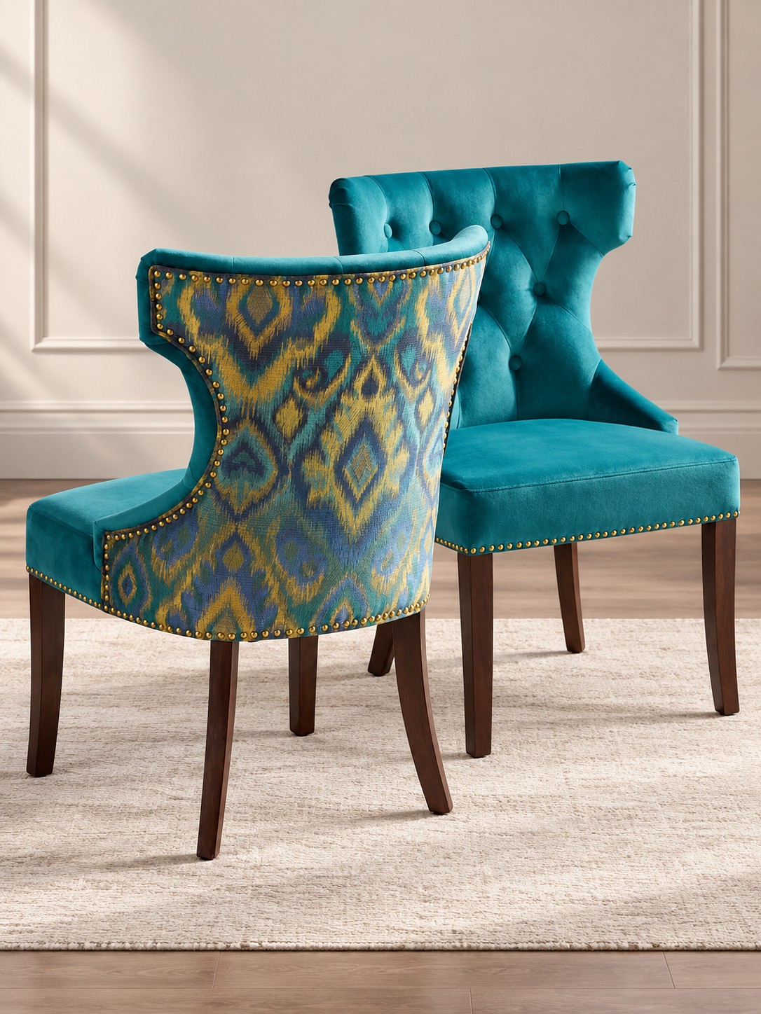 Rich teal upholstery meets patterned backs in shades of blue and ochre. Button detailing, gold-toned studs and dark legs give these chairs character from every angle.